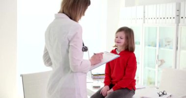 Küçük bir kız bir çocuk doktoruna gülümsüyor, yakın çekim. Çocuk sağlığı ve yavaşlama muayenesi