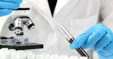 Eczacı, bir şişenin içine toprak damlatan bir pipet damlatıyor. Yakın plan. Kimyasal bir laboratuvarda gübre analizi