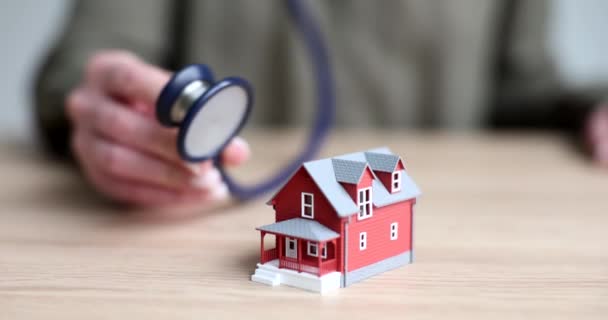 Stethoskop Und Modell Des Roten Hauses Auf Dem Tisch Großaufnahme — Stockvideo