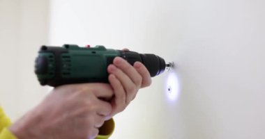 Usta, beyaz duvarda bir delik açıyor, yakın plan. Dairedeki tamirat işleri, yavaş çekim.