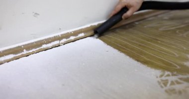 Usta, elektrikli süpürgeyle inşaat tozu topluyor, yakın plan. Tamir sonrası temizlik ekipmanları