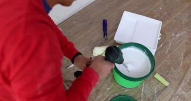 Usta, boyayı elektrikli bir aletle yakın plan çekimle karıştırıyor. Evi boyamak, tamir etmek.