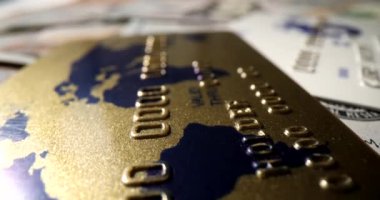 Altın bir kredi kartı, kağıt para ve yakın plan çekimle yatar. Kişisel finansal kaynaklar konsepti, yavaş çekim