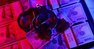 Polis lambası kelepçelerin üzerinde parlıyor ve para dolarları kanlı yakın çekim 4K film yavaş çekim. Yasadışı para satışı 