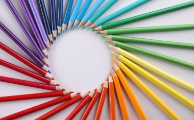 Colored pencils in acircle closeup. Colored pencils lie around on white background. Pencil drawing concept clipart