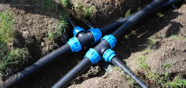Connecting HDPE plastic water pipes in garden. Irrigation system and plastic pipes in ground