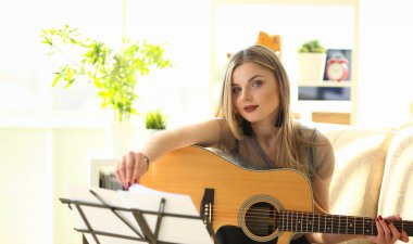Genç kadın gitar çalmayı öğreniyor. Müzik konsepti öğreniliyor
