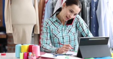 Moda tasarımcısı kadın atölyedeki akıllı telefondan sipariş alır. Kıyafet konseptinde onarım ve terzilik