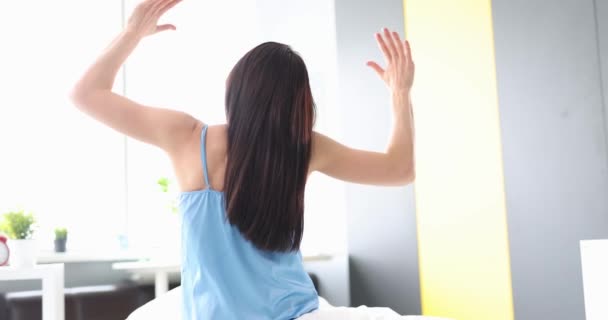 若い女性がベッドに座っている間に手を上げます 正の日の概念を開始 — ストック動画