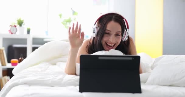 Wanita Ceria Dengan Headphone Berkomunikasi Melalui Panggilan Video Saat Berbaring — Stok Video