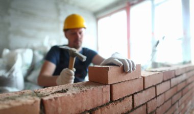Büyük beton duvar inşa ve düzgün bir şekilde bitmemiş yapı üzerine tuğla döşeme katmak için görevi yerine getirmek için özel çekiç kullanarak yetenekli adam Portresi. Bina konsepti
