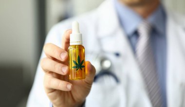 Erkek doktor marihuana yağı tıp hastanesi ofis closeup ile şişe tutun. Amaç narkotik ilaçlar kavramı