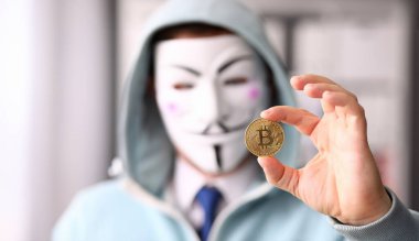 Tiflis, Gürcistan, Haziran 2023: Hacker anonim maske takıyor elinde illüstrasyon editörü olarak Bitcoin bulunduruyor