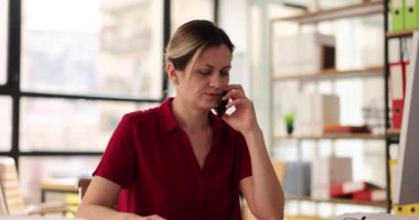 Kadın çalışan, şirket ofisindeki masada telefonla patronla konuşurken başını sallıyor. Müşteri yavaş çekim ile ciddi işçi kontrolleri çevrimiçi sipariş ayrıntıları