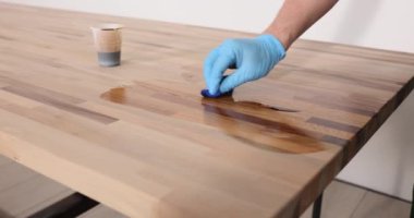 Lastik eldivenli bir çalışan, ofis işyerindeki ahşap zemin yüzeyiyle cilalıyor. Marangoz sıvı lakquer yavaş çekim kullanır.