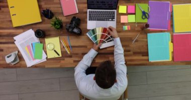 Erkek çalışan modern ofisteki ahşap masada oturan parlak renk paletini inceliyor. Renk konsepti. İç mimarlık mesleği yavaş çekim
