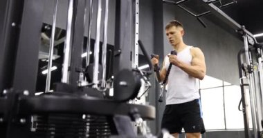 Sporcu modern spor salonunda silah pompalamak için eğitim makinesini kullanır. Spor giyim sektöründe formda bir erkek ağır çekimde egzersiz ekipmanı kullanır.