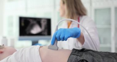 İlgili doktor çocuğun midesini modern ultrason cihazıyla kontrol ediyor. Kadın, patolojik süreçlerin varlığı için ekran inceleme organlarına bakıyor.