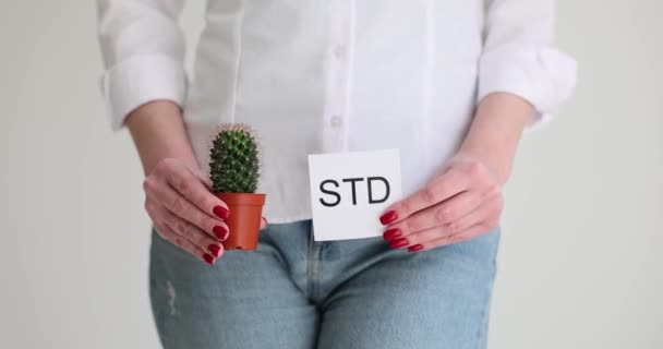 女性はStd碑文とポットと紙にサボテンを保持しています 性感染症による症状や痛みを感じる女性の動きが遅い — ストック動画
