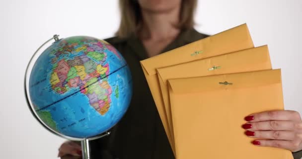 白い背景に地球のモデルと紙の封筒を持つ女性 国際郵便サービスと郵便配達の概念 世界郵便産業 — ストック動画