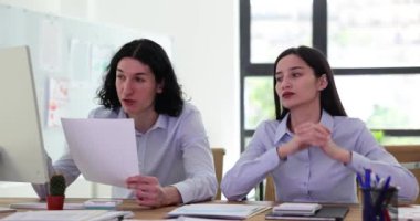 Birkaç ofis çalışanı kağıtları tartışıyor ve çözümleri değerlendiriyor. Sinirli erkek müdür yüksek sesle rapor okur ve bayan iş arkadaşı düşünceli bir şekilde dinler.