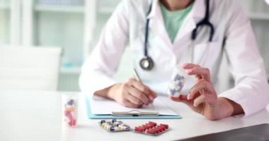 Doktor panoya ilaç şişesiyle tedavi planı yazıyor. Laboratuvar önlüğü uzmanı, klinikteki hastaya ağır çekimde ilaç yazıyor.