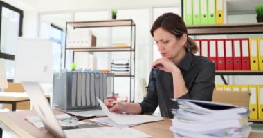 Kadın yönetici, modern önermelerle masa imzalamak için sözleşmeyi dikkatlice inceler. Kadın ofis çalışanı kadehleri ağır çekimde tutan verileri kontrol ediyor.