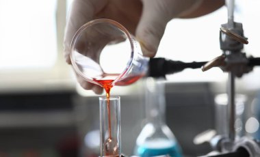 Steril eldivenli erkek eline odaklan. Ampulün içine kırmızı sıvı naklediyor. Eczacı ilaçlarla deney yapıyor. Sağlık ve tıp konsepti. Bulanık arkaplan