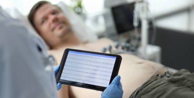 Kadın doktor, yetişkin beyaz hasta elektrokardiyogram görüntüsüyle el bilgisayarında. Kalp hastalığı tedavi konsepti