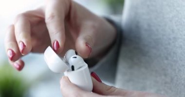 Beyaz kablosuz kulaklıkları kutudan çıkaran kadın 4K 'lık filmi yavaş çekimde çekiyor. Modern müzik dinleme aksesuarları kavramı