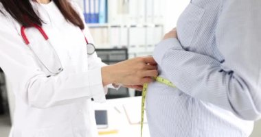 Doktor kadın doğum uzmanı-jinekolog, 4K bantlı film kullanarak hamile bir kadının karnının hacmini ölçüyor. Hamile kadın kavramının tıbbi denetimi