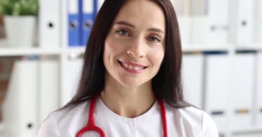 Klinik 4K filminde beyaz üniformalı gülümseyen kadın terapistin portresi ağır çekimde. Meslek doktoru konsepti
