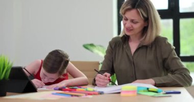 Çekici anne ve küçük kız renkli kalemlerle kağıda resim çiziyorlar. Sevgi dolu aile iletişimden ve ortak yaratıcı hobiden hoşlanır.