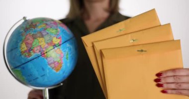 Sarı posta zarfında kadın eli küresi var. Uluslararası belge ve posta teslimatı