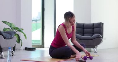 Halterli aktif atletik kadın kaslarını ve pazılarını şişiriyor ve telefonla mesajlaşarak dikkati dağılıyor. Spor hedefinin tutturulması ve spor kasılmalarının kaybedilmesi