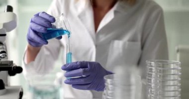 Laboratuvar asistanı mavi kimyasalı test tüpüne döküyor. Kimya endüstrisinde bilimsel araştırma