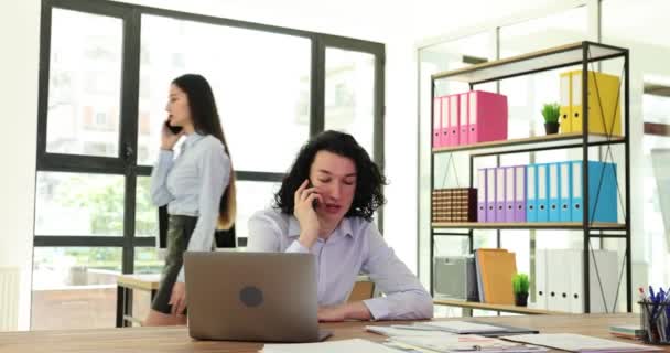 Jovem Empresário Está Falando Telefone Enquanto Senta Mesa Trabalha Laptop — Vídeo de Stock