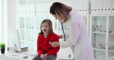 Pediyatrist steteskoplu küçük bir kızın ciğerlerini dinler. Çocuklarda sağlık izleme