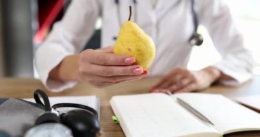 Doktor lezzetli sarı armudu elinde tutuyor. Sağlıklı yemek ve diyet