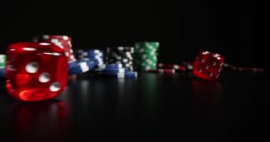 Çok renkli poker fişleri olan kırmızı zarlar karanlık masaya saçılmıştır. Kumarhanede kumar.