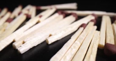 Koyu arkaplanda bir yığın tahta kibrit. Ahşap kibritler ateş yakmak ya da yemek pişirmek için