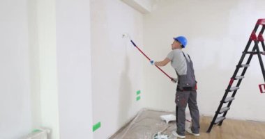 Boyacı inşaat alanında patenciyle duvar boyuyor. Duvar boyası