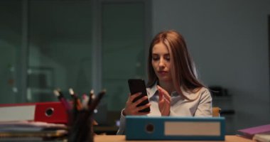 İş kadını cep telefonuyla mesaj yazıyor. 4K gece yarısı ağır çekimde. Müşteri konsepti ile uzak çalışma