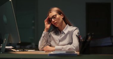 Yorgun iş kadını, gece geç saatlerde iş yerinde bilgisayarın önünde gözlüklerini çıkartıyor. Ağır çekimde. Bilgisayarda uzun süre çalışırken görme sorunları