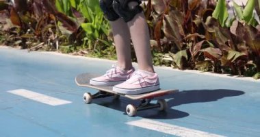 Kız çocuğu güneşli bir havada sokakta kaykaya biner. Kaykay konseptini öğrenme