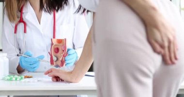 Doktor bağırsak sorunları ve sağlıksız rektum modeli olan bir hastaya reçete yazıyor. Hemoroit kabızlık sorunu ve tedavi