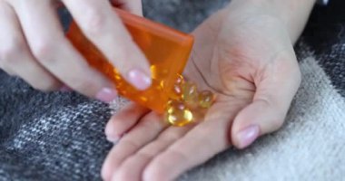 Kadın sarı kapsülleri omega-3 ile dolduruyor. Kız balık yağı konseptini alıyor.