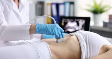 Klinikteki kadının karın boşluğunda ultrason teşhisi. Doktor ultrason sondasını hastanın karnına geçirir ve tarama panelinde çalışır. İç organların teşhisi.