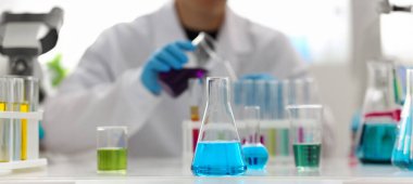 Erkek kimyager tutan tüp elinde cam taşmaları potasyum permanganat yürüten bir analiz tepki alır çeşitli sıvı bir çözüm kimyasal üretim kullanarak reaktifler sürümleri.