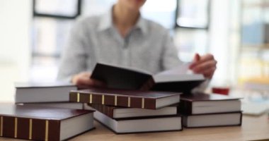 Kadın çalışan, ofisteki ahşap masada oturan ekonomi araştırmaları için kitap sayfalarını çeviriyor. İş kadını ticari yavaş çekim dizininde bilgi istiyor